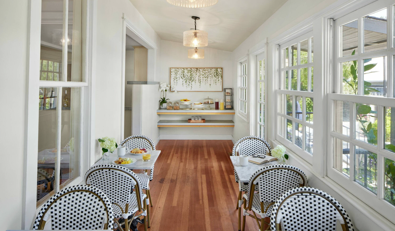 A beautiful breakfast nook features two rows of tables in a narrow, airy hardwood room with windows on either side | Hotel Yountville