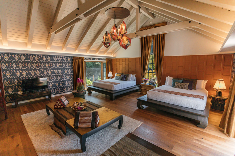 A stylishly designed guest room with two beds, high wooden beam ceilings, and warm tones | Hotel Yountville
