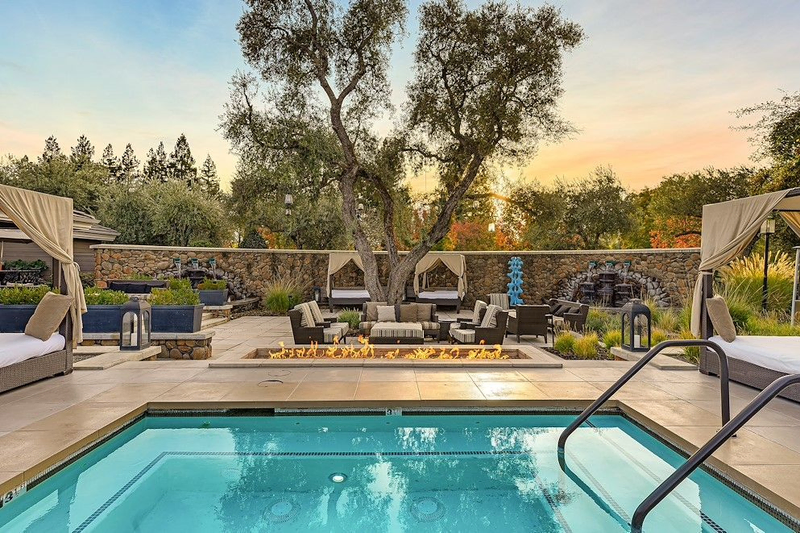 A gorgeous pool surrounded by stone walls, a firepit, and areas to relax in canopied luxury | Hotel Yountville