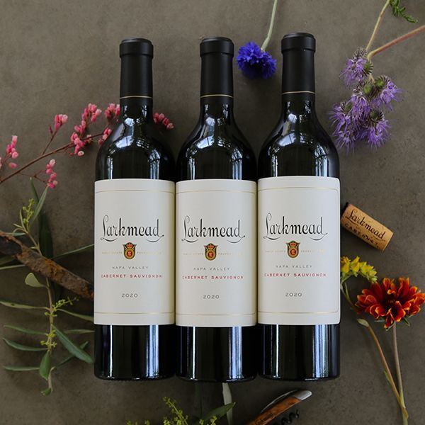 Three bottles of Larkmead 2020 Cabernet Sauvignon surrounded by flowers.