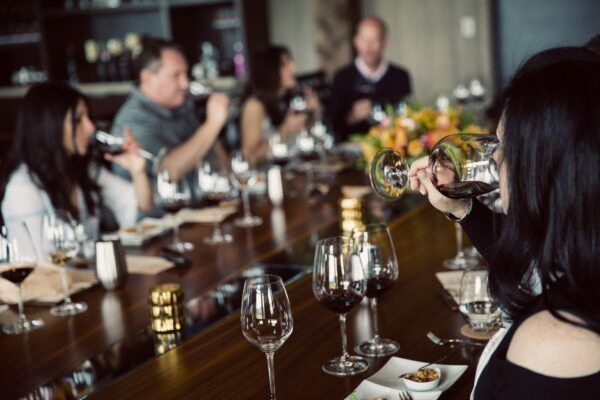 Group of people enjoying a wine tasting experience at a long table.