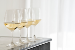 Four glasses of white wine on a marble surface.