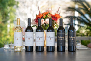 A selection of wine bottles displayed on a table with flowers in the background.