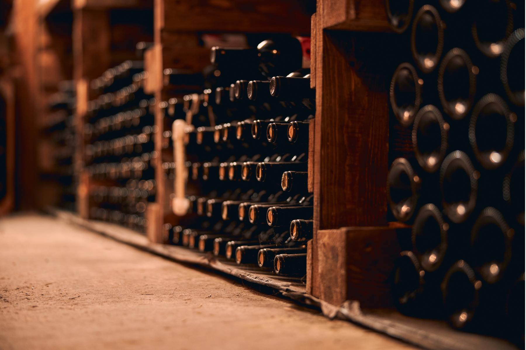 A rustic wine cellar with rows of wine bottles stacked on wooden shelves, showcasing a warm, earthy ambiance.