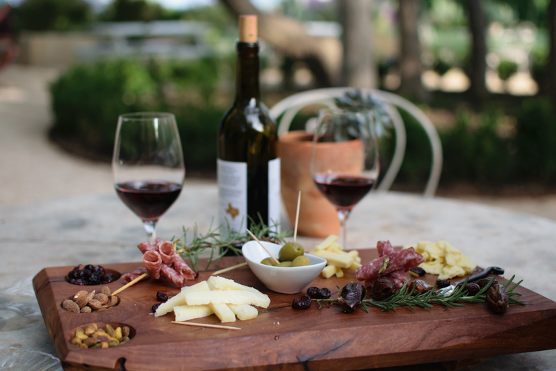 A wine and charcuterie board with two glasses of red wine outdoors at Davis Estates.