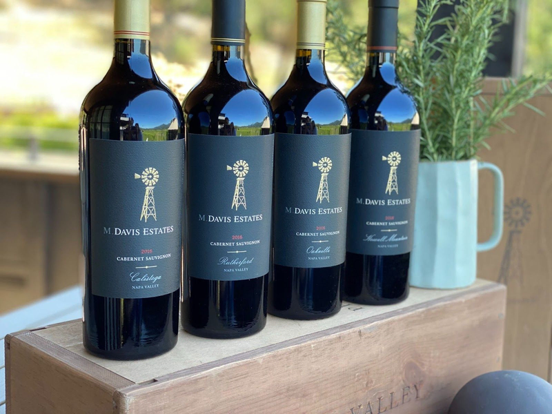 Four M. Davis Estates Cabernet bottles displayed on a wooden box.