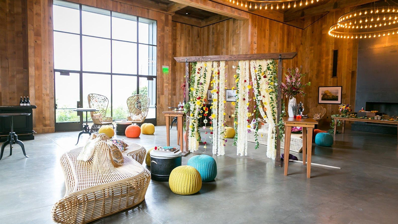 Stylish event space with rustic wooden walls, floral decor, and cozy seating.