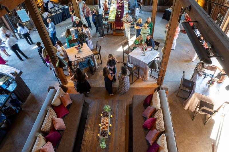 Rustic winery event with guests mingling in a warm, wooden barn setting.